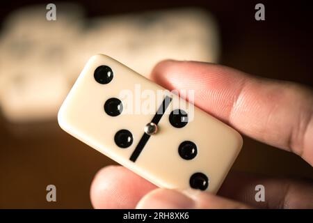 Primo piano delle piastrelle Domino in mano. Domino è uno dei giochi classici più famosi. Riprese in condizioni di scarsa illuminazione e profondità di campo ridotta. Foto Stock