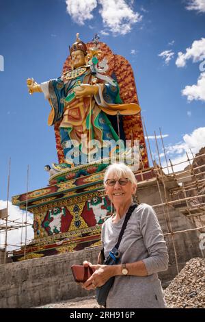 India, Jammu e Kashmir, Ladakh, Bodhkharbu, anziana turista sotto la statua gigante di Guru Padmasambhava in fase di ristrutturazione Foto Stock