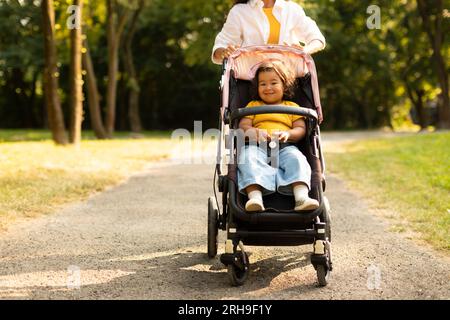 Mamma asiatica che va con la bambina figlia in Stroller a Park Foto Stock