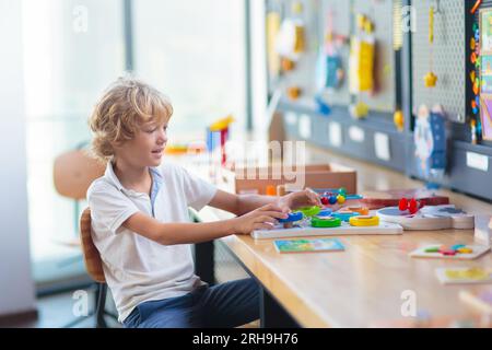 Bambino con giocattoli educativi a scuola. Corso di scienze o club di robotica per giovani studenti. Bambino con un gioco di puzzle matematico. Foto Stock