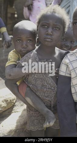 Bella foto di una sorella africana che le tiene il fratello minore sulla schiena. assomiglia al profondo senso di cura della nostra natura umana. povertà. Foto Stock