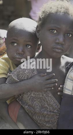 Bella foto di una sorella africana che le tiene il fratello minore sulla schiena. assomiglia al profondo senso di cura della nostra natura umana. povertà. Foto Stock