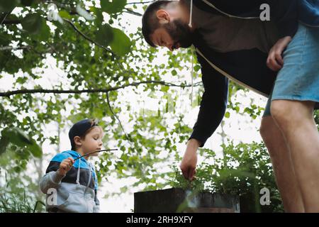 bambino e padre che grigliano carne al barbecue e picnic all'aperto. Foto di alta qualità Foto Stock