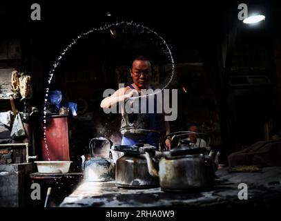 (230815) -- CHENGDU, 15 agosto 2023 (Xinhua) -- li Qiang, l'attuale proprietario della casa da tè Guanyinge, lancia l'acqua nell'aria per creare una forma nella casa da tè Guanyinge nel distretto di Shuangliu di Chengdu, capitale della provincia del Sichuan della Cina sud-occidentale, 7 agosto 2023. Guanyinge, situata sulla riva di un fiume in un'antica strada nel distretto Shuangliu di Chengdu, è una casa da tè con una storia di oltre cento anni. Il nome della casa da tè, Guanyinge, deriva da un racconto popolare, in cui si dice che grazie alla benedizione del Bodhisattva Avalokitesvara (Guanyin), la casa da tè sopravvisse ad un f Foto Stock