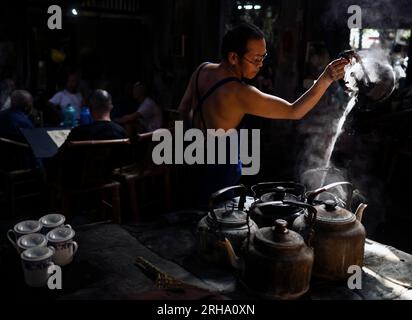 (230815) -- CHENGDU, 15 agosto 2023 (Xinhua) -- li Qiang, l'attuale proprietario della casa da tè Guanyinge, versa acqua in una pentola nella casa da tè Guanyinge nel distretto di Shuangliu di Chengdu, capitale della provincia del Sichuan della Cina sud-occidentale, 7 agosto 2023. Guanyinge, situata sulla riva di un fiume in un'antica strada nel distretto Shuangliu di Chengdu, è una casa da tè con una storia di oltre cento anni. Il nome della casa da tè, Guanyinge, deriva da un racconto popolare, in cui si dice che grazie alla benedizione del Bodhisattva Avalokitesvara (Guanyin), la casa da tè sopravvisse a un incendio cento anni fa Foto Stock