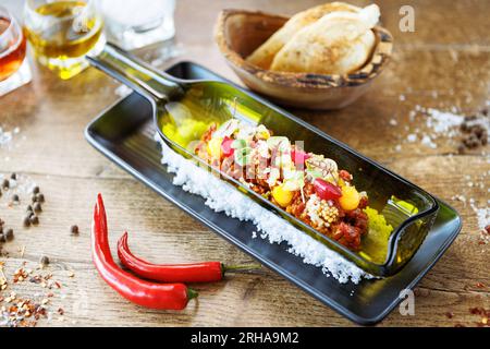Tartare di manzo dal Black Angus. Tuorlo d'uovo, cetriolo sottaceto, scalogno, cipolla perlata, coriandolo e semi di senape. Cibo italiano delizioso e salutare servito Foto Stock