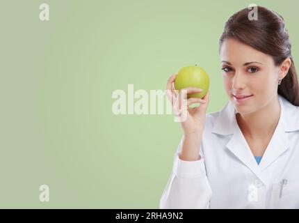 Nutrizionista femminile professionista che tiene una mela verde e sorride, dieta e concetto di alimentazione sana, copia spazio Foto Stock