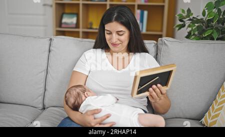 Madre e bambina seduti sul divano guardando la cornice di casa Foto Stock