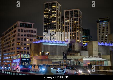 LONDRA - 22 aprile 2023: Londra in movimento: Assisti all'iconico autobus rosso che attraversa il Waterloo Bridge, incorniciato dalla Hayward Gallery e dagli appartamenti della città, a notte Foto Stock