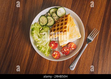 Verdure a fette con uova strapazzate in un waffle su un piatto bianco con una forchetta Foto Stock