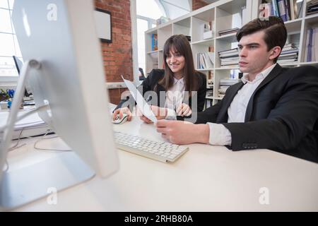 Due uomini d'affari che lavorano insieme usando il computer in ufficio Foto Stock