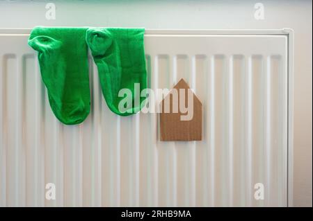 Cartiera e un paio di calze verdi sul radiatore bianco. Alloggi, energia, economia, tema domestico Foto Stock