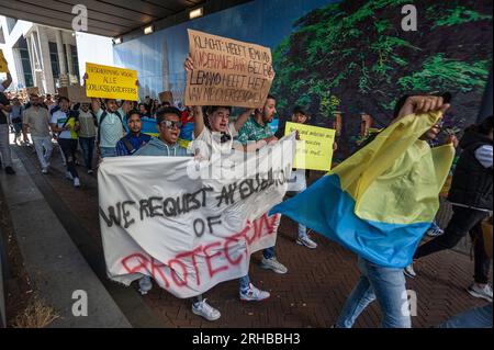 L'Aia, Paesi Bassi. 14 agosto 2023. Gli studenti marciano lungo Rijnstraat tenendo uno striscione, una bandiera Ucraina e cartelli durante la protesta. L'invasione di Putin in Ucraina ha visto non solo l'evacuazione di massa dei suoi indigeni, ma anche l'evacuazione del suo corpo studentesco straniero che studiava in quel paese. Invece di tornare a casa, la maggior parte fuggì nella vicina Europa e più di quattromila entrarono nei Paesi Bassi. All'epoca anche loro avevano ottenuto asilo con diritti simili a quelli concessi ai cittadini ucraini. Gli studenti che avevano presentato una richiesta di asilo ora considerano questa una forma di intrappolamento Foto Stock