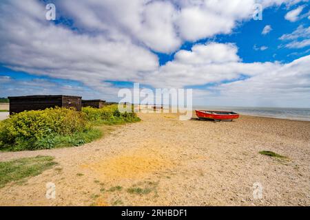 Capanne e barche dei pescatori sulla spiaggia di Dunwich, Suffolk, Inghilterra, Regno Unito Foto Stock