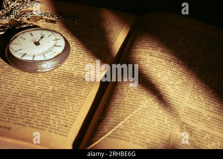 Antico orologio da tasca e antico libro aperto. Oggetti in stile retrò. Orologio argento vintage con catena su libro. Nostalgia. Il passato. Foto Stock