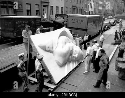 New York, New York: 1940 Isamu Noguchi guarda parte della placca dell'Associated Press Building, che è stata scolpita in gesso e fusa in acciaio inossidabile - all'epoca la più grande fusione di acciaio inossidabile di sempre. È ancora installato nel Rockefeller Center. Foto Stock