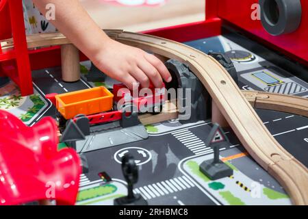 Primo piano del braccio e della mano di un bambino che gioca con un treno giocattolo Foto Stock