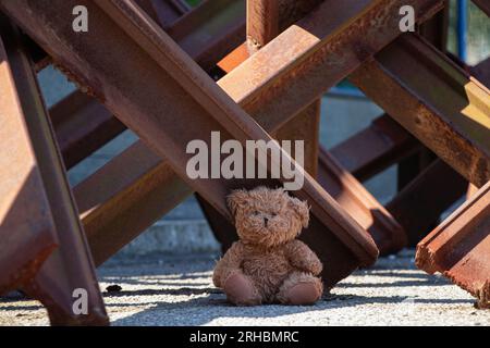 Un orsacchiotto si trova accanto a un riccio anticarro su una strada nella città di Dnipro in Ucraina durante la guerra Foto Stock
