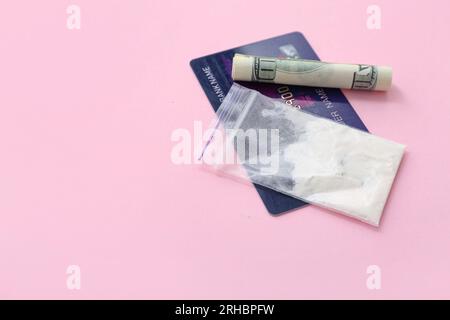 Droga, carta di credito e denaro su sfondo rosa Foto Stock