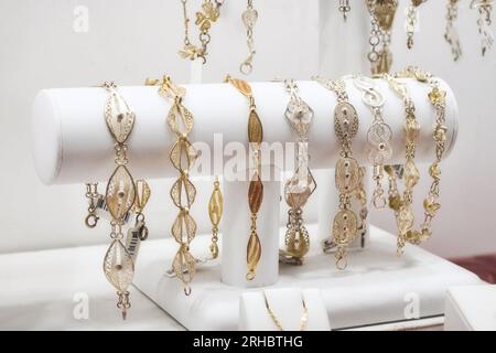 Una collezione di bracciali da donna in filigrana d'oro e d'argento in mostra in una gioielleria al dettaglio Foto Stock