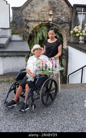 ragazza con donna disabile che porta fiori al cimitero Foto Stock
