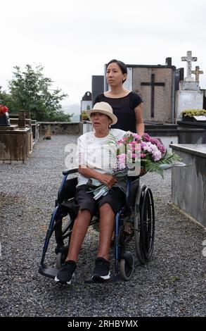 ragazza con donna disabile che porta fiori al cimitero Foto Stock
