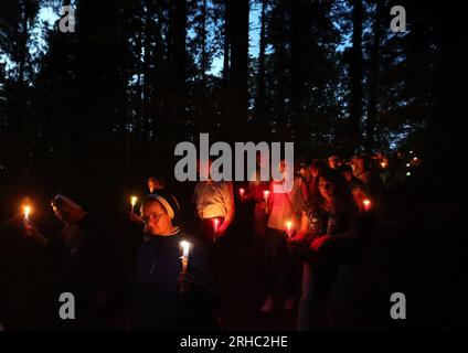 Ziemetshausen, Germania. 15 agosto 2023. I fedeli marciano attraverso la foresta nel luogo di pellegrinaggio di Maria Vesperbild in una processione di luci nell'ambito di una messa pontificia qui celebrata dall'Arcivescovo Gänswein, ex segretario privato di Papa Benedetto XVI, nel giorno della festa cattolica dell'assunzione della Beata Vergine Maria. Credito: Karl-Josef Hildenbrand/dpa/Alamy Live News Foto Stock