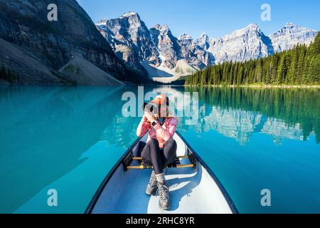 Donna che scatta foto delle montagne circostanti, del lago Moraine durante l'estate nel Parco nazionale di Banff, Canadian Rockies, Alberta, Canada. Banff National P. Foto Stock