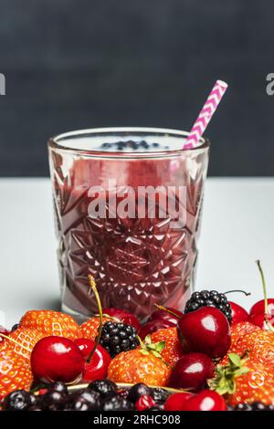 Bicchiere con succo di bacca appena spremuto con ciliegie rosse, more mature e fragole fresche Foto Stock