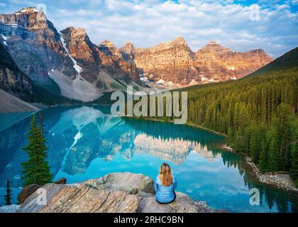 Donna che si gode la calma vista mattutina sul lago Moraine durante l'estate nel Banff National Park, Canadian Rockies, Alberta, Canada. Banff National Park, Alb Foto Stock