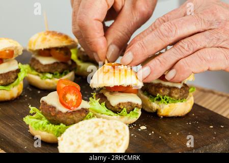 Mettere uno stuzzicadenti sull'hamburger. Preparazione passo-passo dei mini hamburger. Mini hamburger fatti in casa per bambini o antipasti. Piccoli hamburger. Assemb Foto Stock