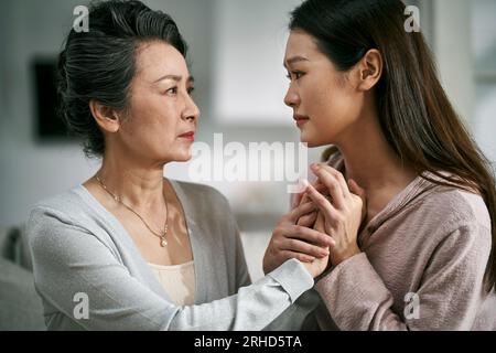 giovane figlia asiatica adulta che consola la madre anziana che vive con una malattia mentale Foto Stock