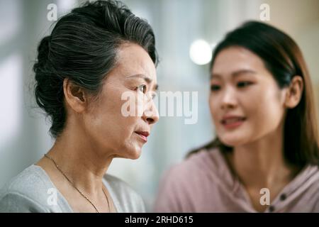 giovane figlia asiatica adulta che consola la madre anziana che vive con una malattia mentale Foto Stock