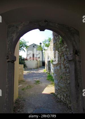 Porta ad arco che conduce in una stretta strada nella piccola cittadina mediterranea di Stanjel, nella regione carsica e litorale della Slovenia Foto Stock