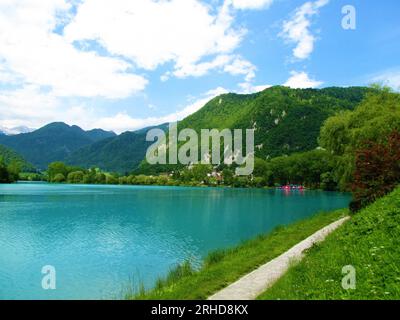 Sentiero a piedi vicino al lago presso Most na Soci nella regione Littoral della Slovenia con montagne coperte di foreste e colline alle spalle Foto Stock