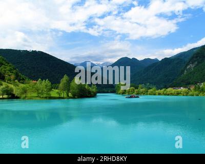 Lago color turchese al massimo na Soci nella regione litorale della Slovenia e montagne delle alpi Giulie alle spalle in estate Foto Stock