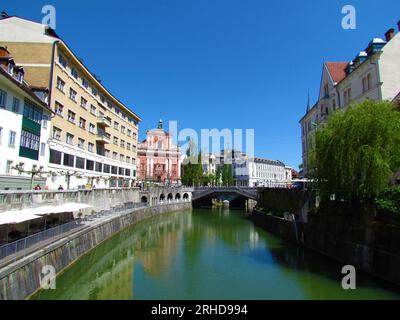 Il fiume Ljubljanica scorre attraverso la città di Lubiana in Slovenia e la chiesa francescana dell'Annunciazione e un riflesso degli edifici nel ri Foto Stock