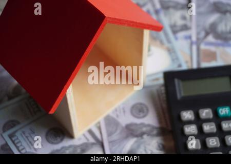 Immagine ravvicinata della casa dei giocattoli, della calcolatrice e del denaro. Concetto immobiliare e immobiliare. Foto Stock