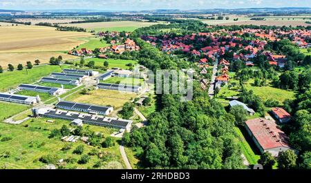 Vista aerea di una moderna fattoria con pannelli solari sui tetti di fronte a un villaggio sulle montagne Harz in Germania Foto Stock