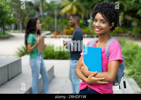 Felice studentessa brasiliana con un gruppo di amici all'aperto nella città tropicale Foto Stock