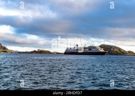 Traghetto Hurtigruten e nave da crociera che naviga nel freddo mare artico, Reine Bay, Isole Lofoten, Norvegia Foto Stock