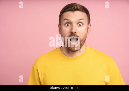 Stupito, eccitato e meravigliato uomo che guarda la fotocamera con un'espressione del volto sorprendente che si sente sorpreso Foto Stock