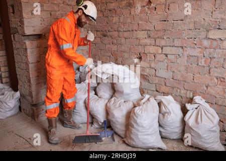 Lavoratore che pulisce il cantiere dopo il lavoro con la scopa. Foto Stock