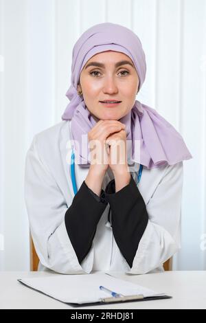 Medico musulmano in hijab con eccitazione lavora in clinica Foto Stock