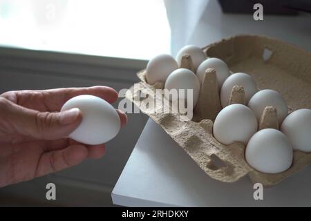 Le mani del vecchio prendono le uova di gallina dal contenitore per cucinare il cibo Foto Stock