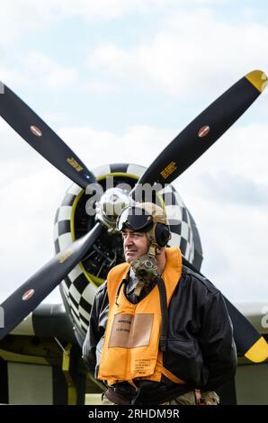 Reenactor vestito con costume da volo USAAF della seconda guerra mondiale con l'aereo P-47 Thunderbolt. Tuta volante con salvagente tipo B-3, casco, maschera Foto Stock