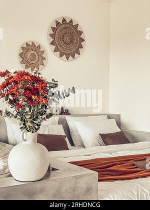 Bouquet di crisantemi d'arancia con foglie di eucalipto vicino al letto con bedrunner di terracotta Foto Stock