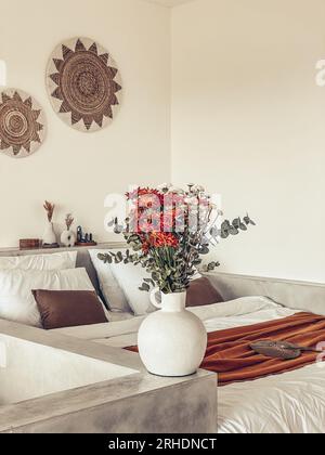 Bouquet di crisantemi d'arancia con foglie di eucalipto vicino al letto con bedrunner di terracotta Foto Stock