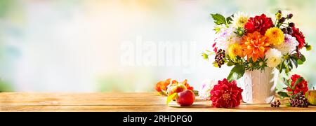 Natura morta autunnale con fiori da giardino. Bellissimo bouquet autunnale in vaso, mele e frutti di bosco su un tavolo di legno. dahlia colorata e crisantemo. Foto Stock
