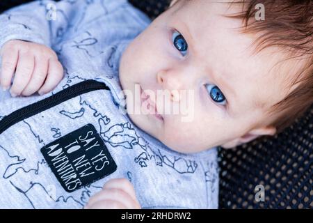 Il bambino dagli occhi blu che guarda in alto con la lettura del body dice di sì alle nuove avventure Foto Stock